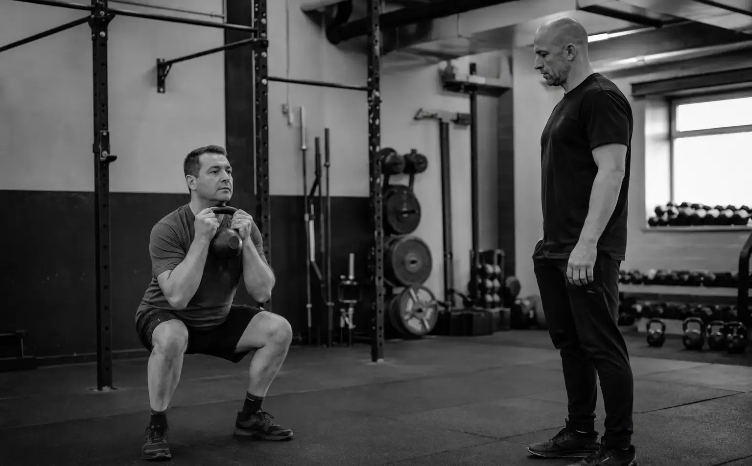 A novice completing a controlled goblet squat while a coach watches