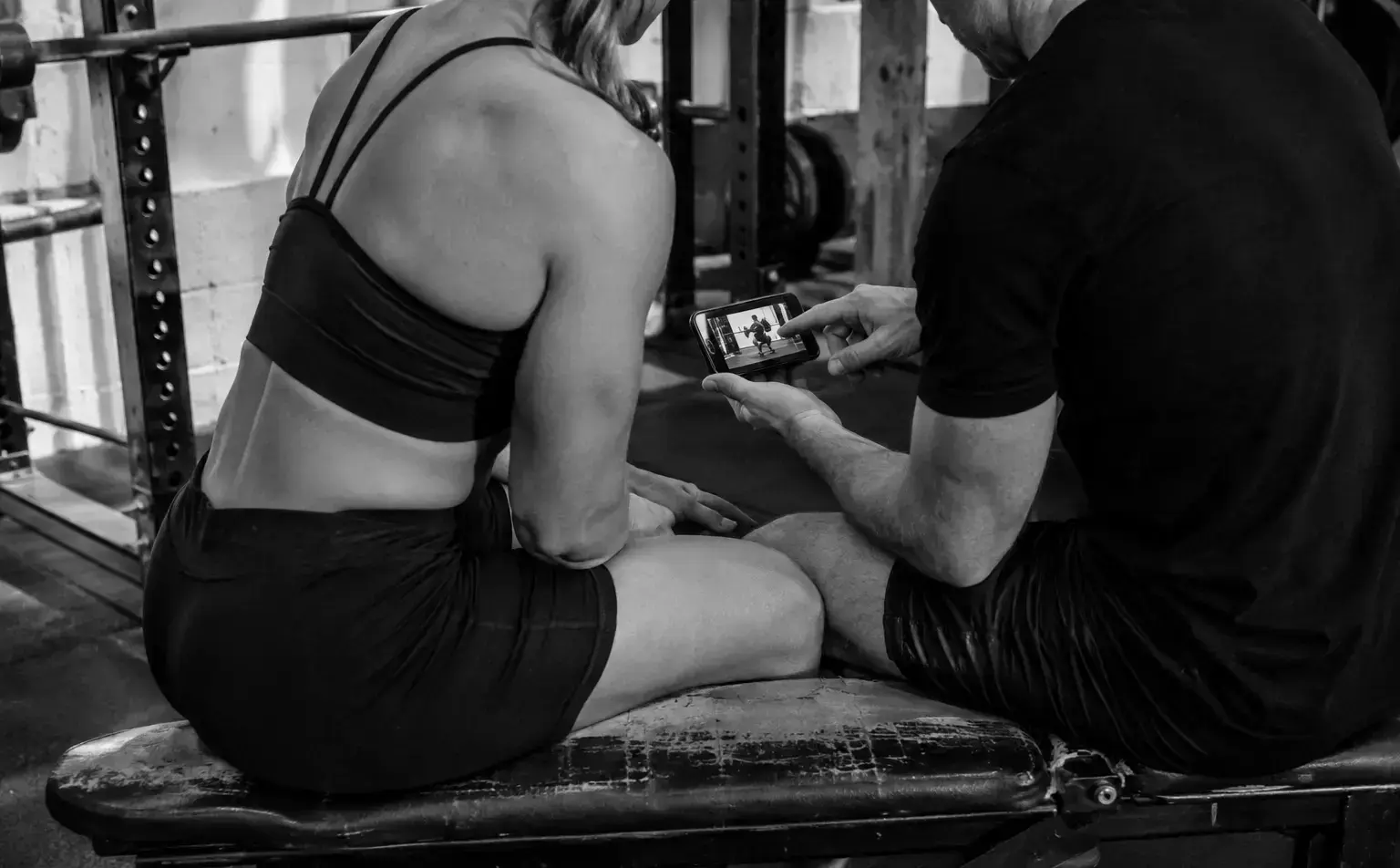 A lifter and coach reviewing squat footage on a phone
